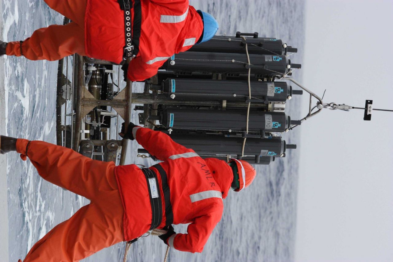 AMLR crew members lower equipment into the frigid ocean. Photo