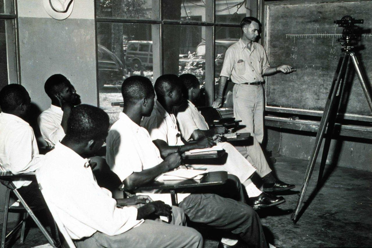 Commander George Morris instructing Liberian engineering students in the use of surveying instruments. Photo