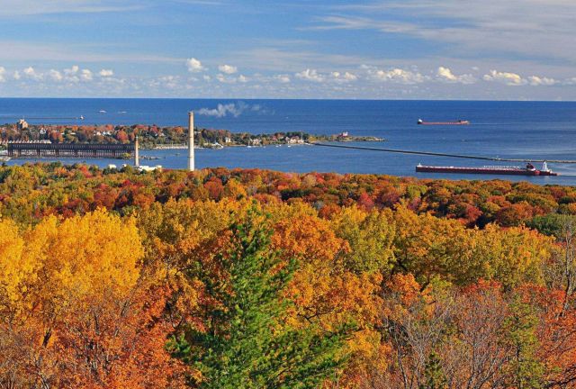 Two large lake bulk carriers arriving at Marquette Harbor with fall foliage in the foreground. Picture