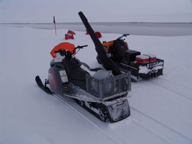 Snow-mobiles used to transport scientists checking sensor array along opening lead. Picture
