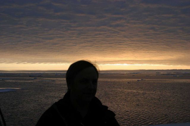 A lone observer with ice floes, open water, and an amazing display of illuminated clouds. Picture
