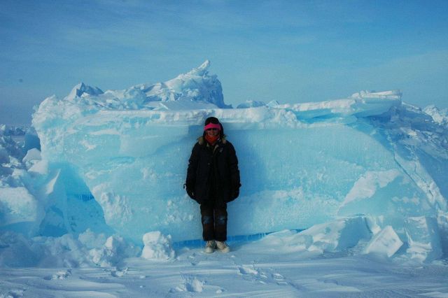 Scientist standing by block of ice for scale on pressure ridge. Picture