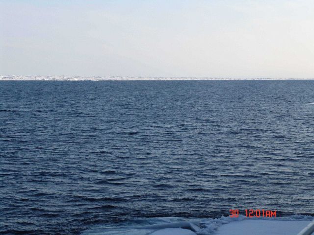 A large area of open water with unbroken ice pack in the distance. Picture