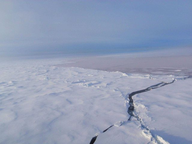 Hummocky multi-year ice with frozen over melt ponds with a fracture opening to an area of new ice. Picture