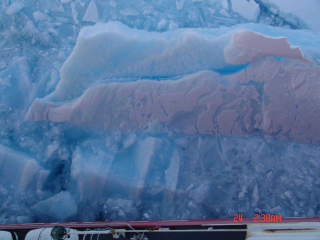 Broken ice with rough sculpted appearance surface next to USCG icebreaker HEALY. Picture