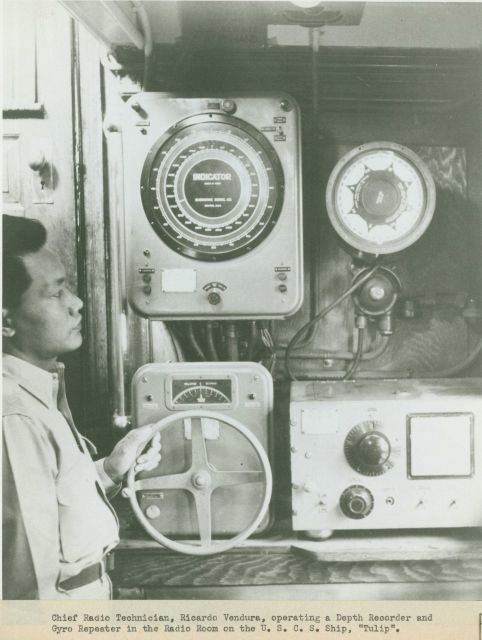 Chief Radio Technician, Ricardo Vendura, operating a depth recorder and monitoring a gyro repeater in the radio room of the U Picture