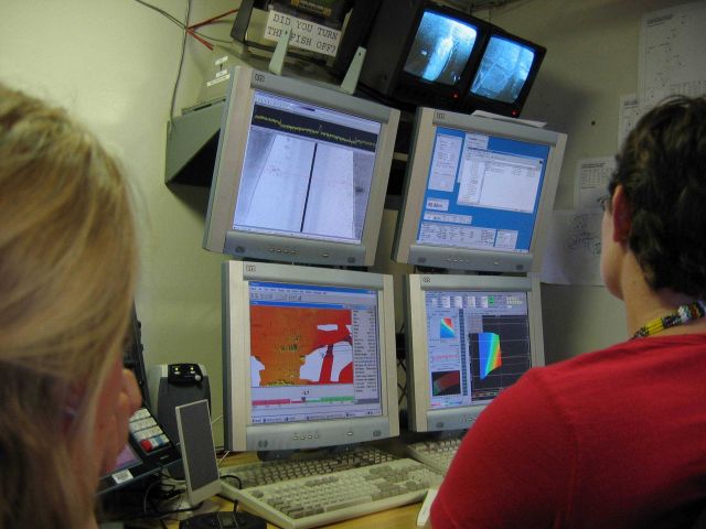 Monitoring survey data on array of computer screens. Picture