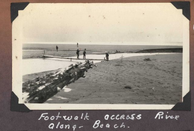 Work party along beach crossing small stream with improvised foot bridge. Picture