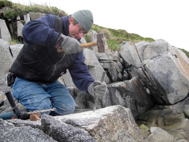 Starting a drill hole with hammer and chisel for placing a survey mark. Picture