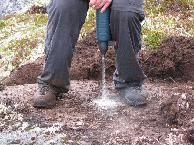 Using a power drill to drill a hole for placing a survey mark. Picture