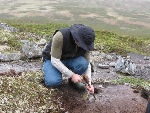 Starting a drill hole with hammer and chisel for placing a survey mark. Picture