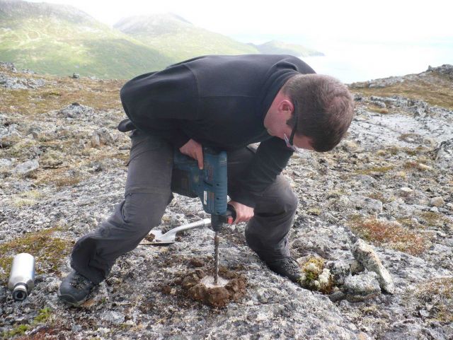 Using a power drill to drill a hole for placing a survey mark. Picture