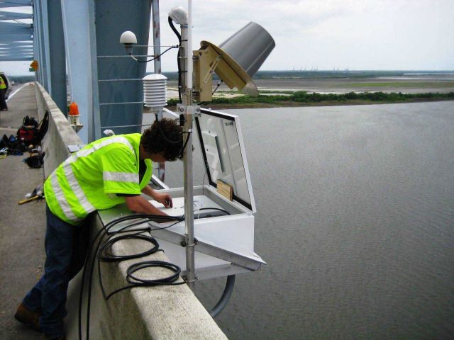 An employee of NOAA's Center for Operational Oceanographic Products (CO-OPS) installs an air gap sensor on the Don Holt Bridge Picture