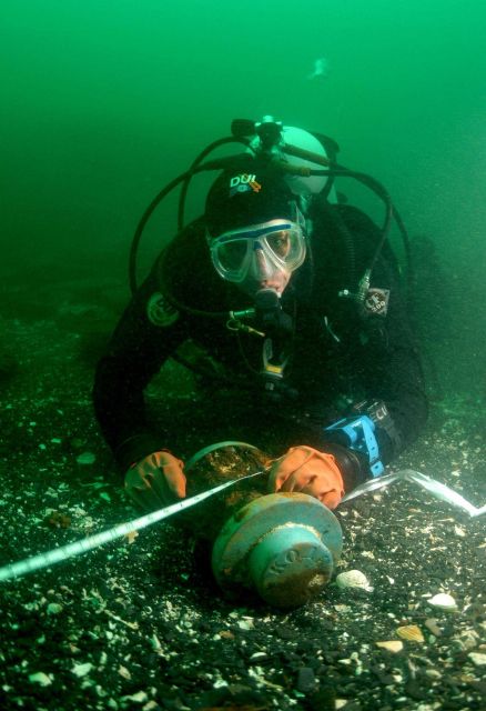 Steve Sellers, Diving Safety Officer of East Carolina University, holding measuring tape to map location of Kad'yak's hub prior to recovery for preser Picture