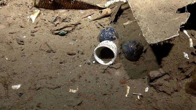 The black two-bulbed object is an hourglass with a white cup in front of it Picture