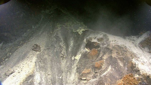 Hydrothermal vent area covered with white bacterial mat and hydrothermally altered rocks and minerals. Picture