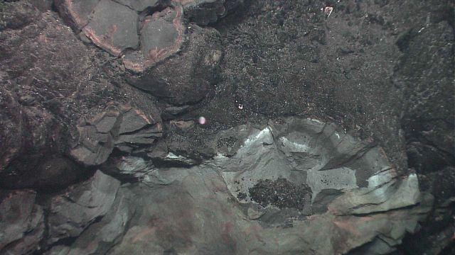 Circular patterns in rock outcrop with indications of hydrothermal alteration. Picture