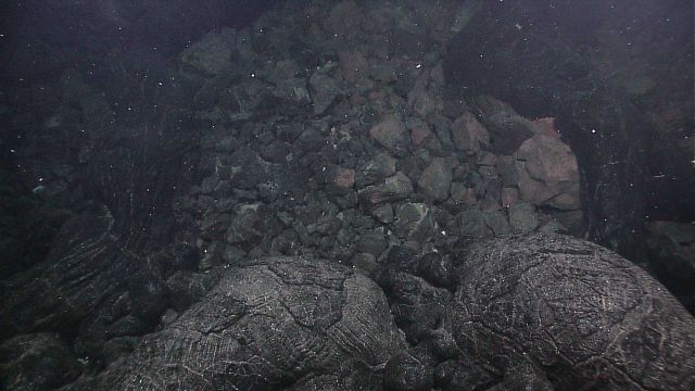 Classic pillow lavas in foreground with hydrothermally altered material in background. Picture
