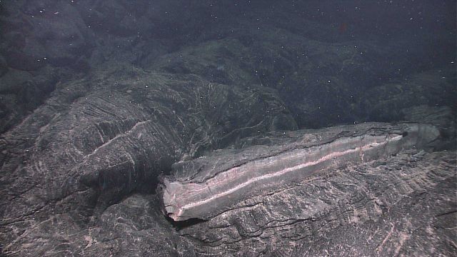 An oddly broken lava slab showing cooling zones of lava and pink and white alteration. Picture