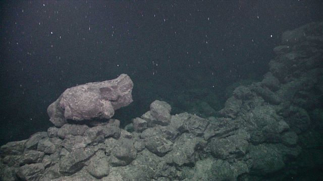 Lone lava boulder lying on ridge of angular volcanic rock. Picture