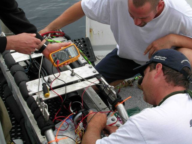 Dave Read, Matt Barnhart, and John Harms work on an underwater camera system aboard the F/V SEAHORSE. Picture