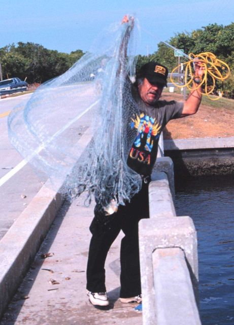 Photo -5a - A fisherman retrieving his net after casting for mullet and other fish off a bridge south of Everglades City. Picture