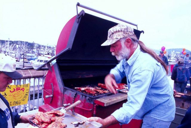 A crewman offers up grilled salmon at a dockside barbecue in Kodiak, Alaska, to benefit his fishing organization. Picture