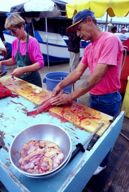 Family affair fish market as husband and wife fillet fish. Picture