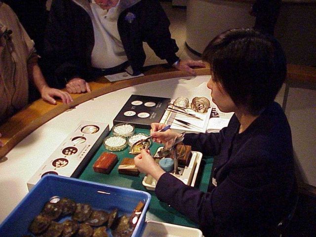 Technician demonstrating the process of pearl removal from a cultured pearl. Picture