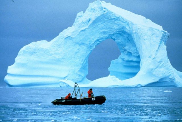 Driving a Zodiac past a spectacular iceberg. Picture