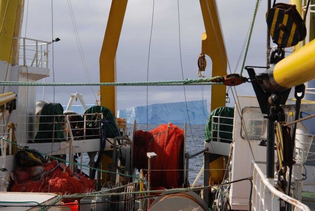 An iceberg is visible through the A-frame of the R/V Yuzhmorgeologiya. Picture