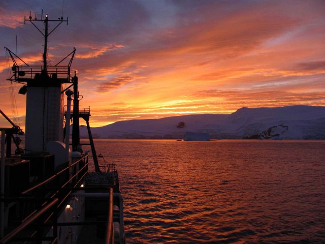 The sun rises over the R/V Moana Wave in Discovery Bay, Antarctica. Picture