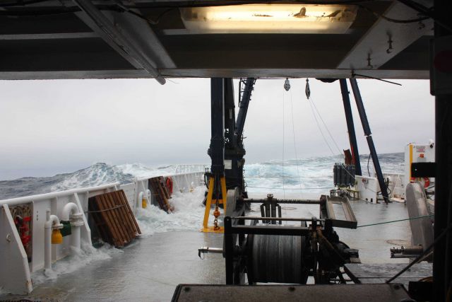 During rough seas, waves crash over the side of the R/V Moana Wave flooding the stern of the ship Picture