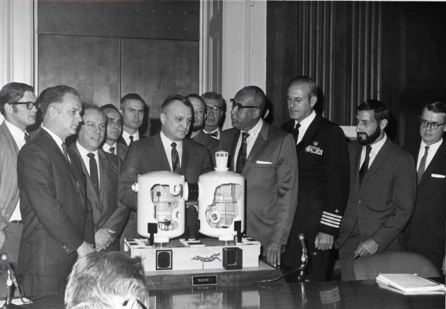 Wally Hickel, Secretary of the Interior, with other dignitaries and Tektite aquanauts inspecting a model of the Tektite II manned undersea habitat. Picture