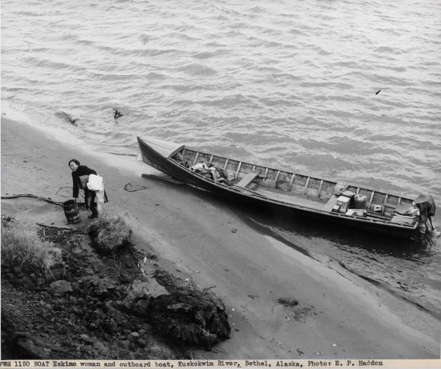 Eskimo woman and outboard boat on the banks of the Kuskokwim River at Bethel. Picture