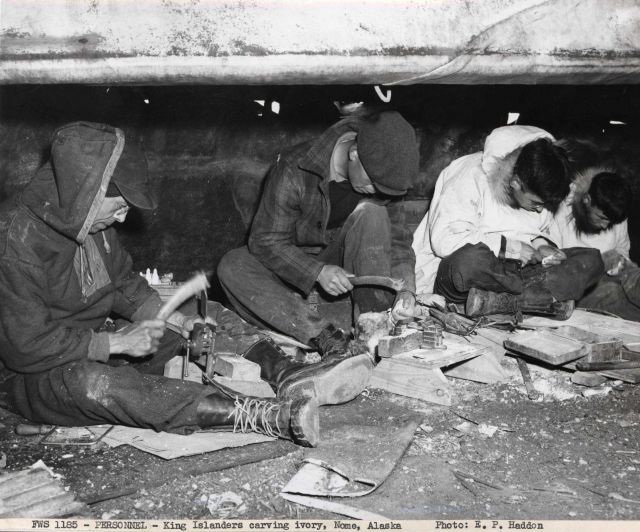 King Islanders carving ivory beneath the skin-covered umiaks on the beach at Nome where they have a summer camp. Picture