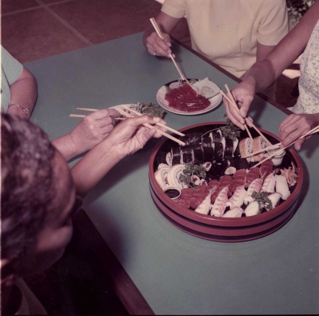 Diners trying to use chopsticks at sushi bar Picture