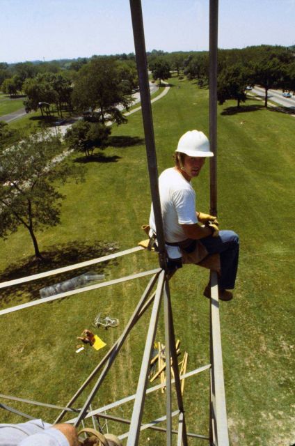 Builder sitting on construction seat setting leg - not a good job for folks with acrophobia! Picture