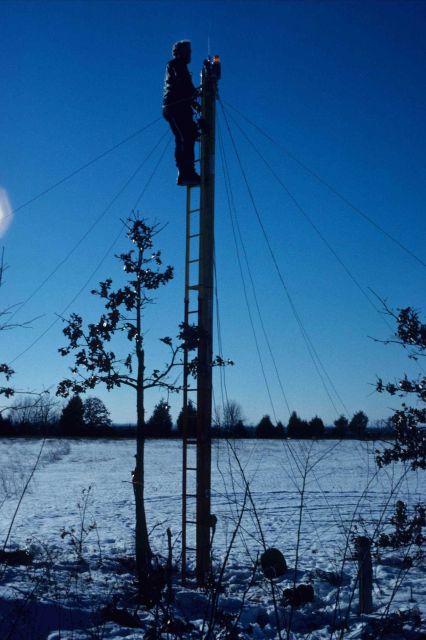George Leigh atop pole's ladder installing survey equipment and hooking up electrical connections Picture