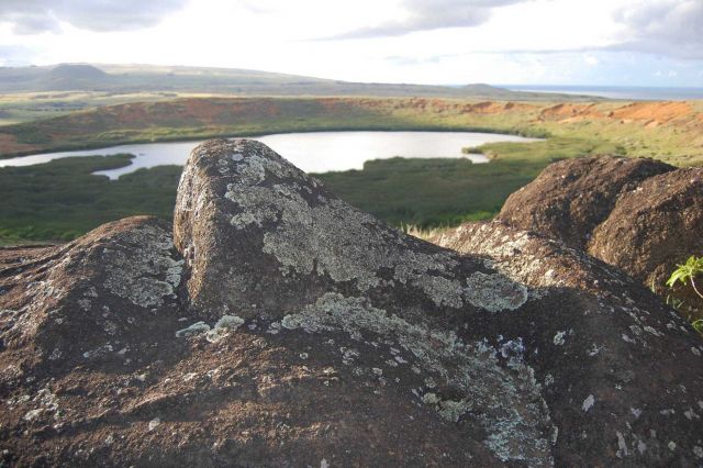 Lichen-covered rocks overlooking a small volcanic crater lake and marsh. Picture