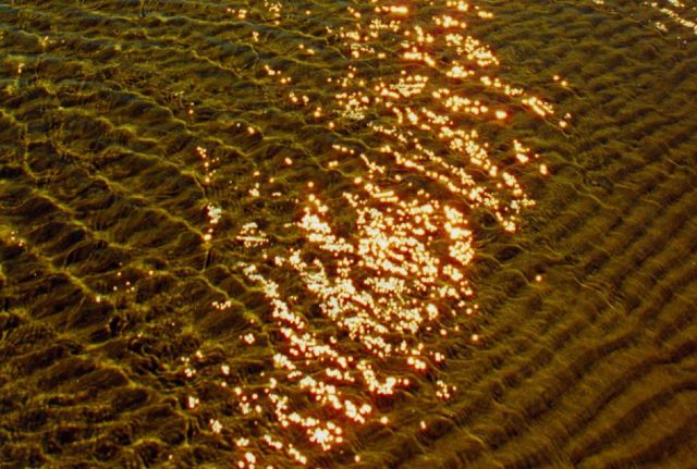 The swash zone at Nanny Goat Beach showing ripple pattern in sand and sunlight reflecting off the water Picture