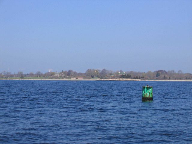 Long Island shoreline looking past a buoy to mansions on the shore. Picture