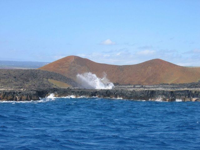 A blowhole shooting out water from the action of waves entering a subterranean passage. Picture