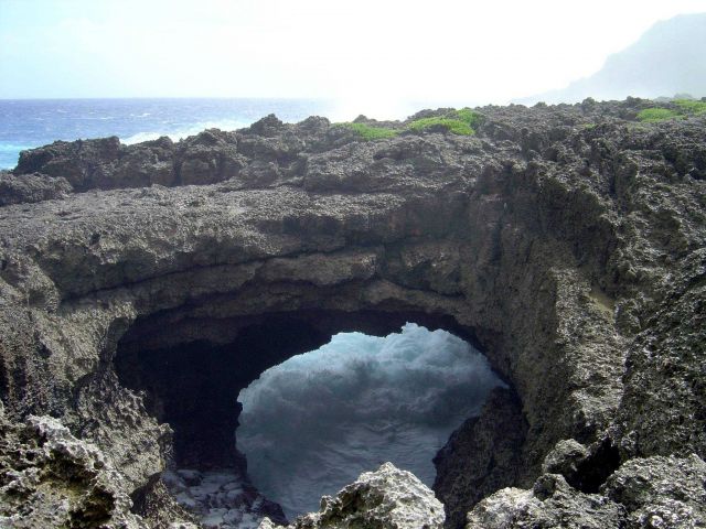 Roaring surf seen through a beautiful natural stone arch on the coast of Guam. Picture