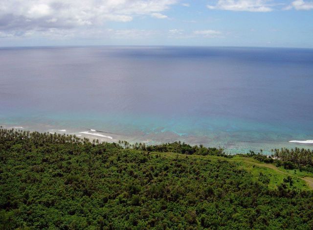 Looking down over the Guam jungle to the reef and surf far below. Picture