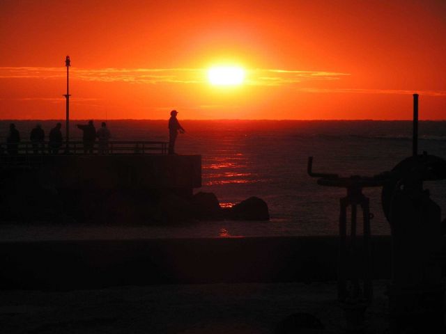 Jupiter Inlet sunrise with fisherman silhouetted. Picture