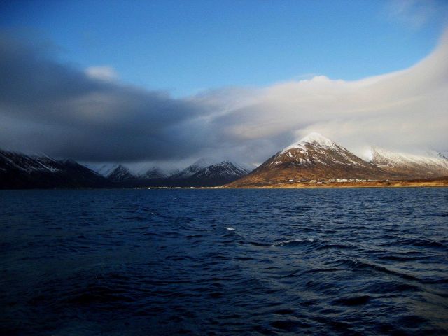 Departing King Cove with cloud shrouded, snow covered mountains in distance. Picture