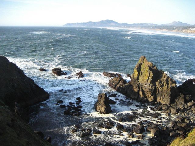 Whitecaps, wind, surf, and a rocky shore. Picture