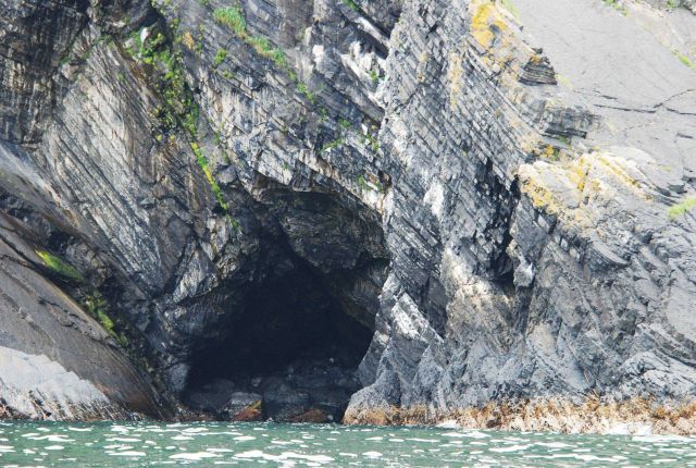 Tilted sedimentary beds and a large sea cave. Picture