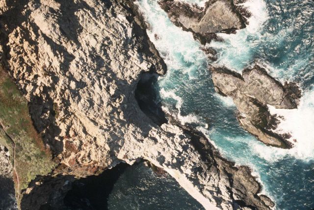 Unidentified rock headland with sea cave. Picture
